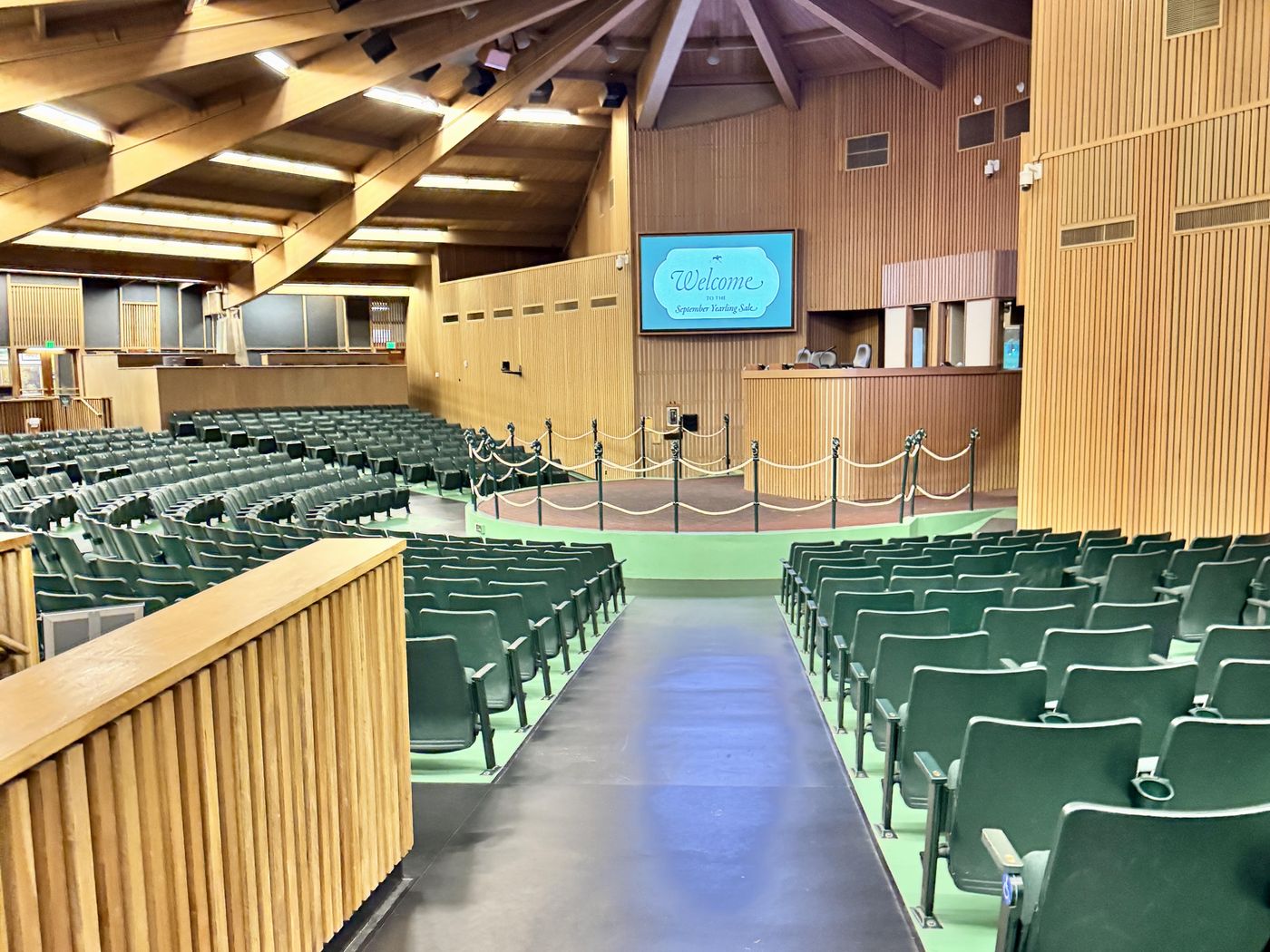 The empty Keeneland sales ring after a session, green seats rising around the auctioneer's stand.